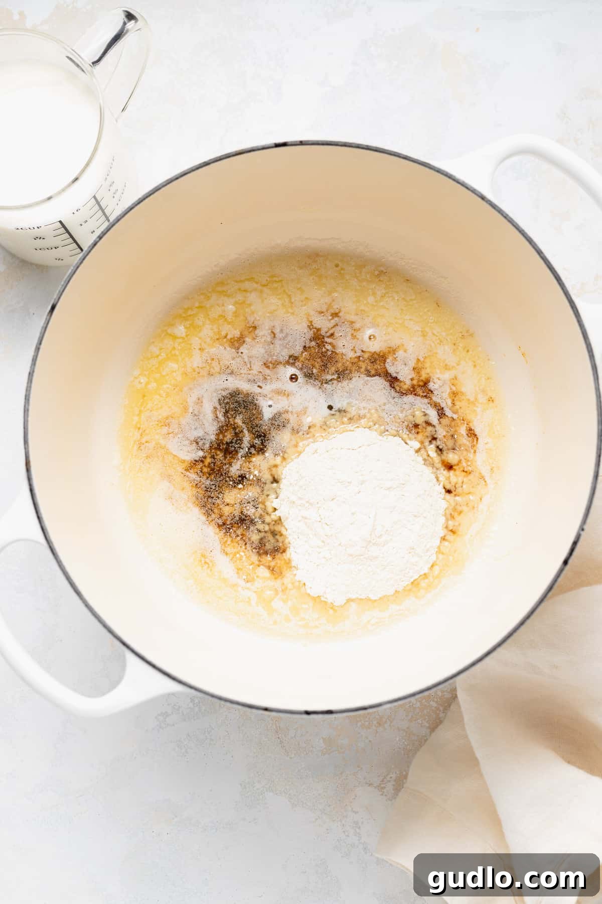 A Dutch oven on a stovetop, showing the initial stages of making a roux for mac and cheese.