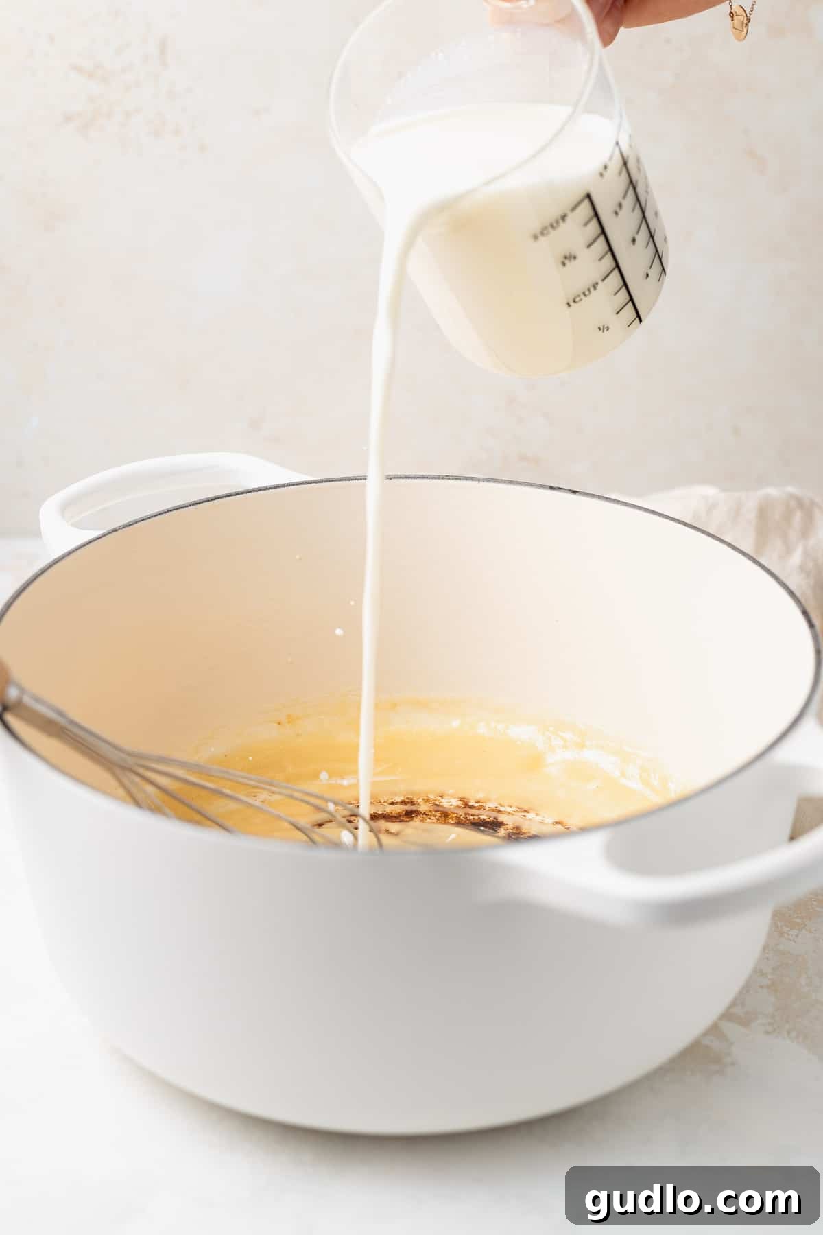Pouring milk into a Dutch oven to create a creamy roux for white cheddar mac and cheese.