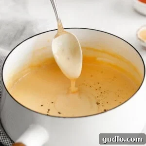 A pot of rich, bubbling cheese sauce, perfect for dipping or mixing with pasta.