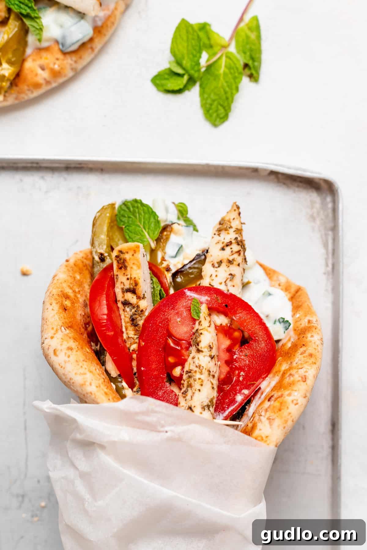 Sheet Pan Mediterranean Chicken Gyros 7 Close-up of a beautifully wrapped sheet pan chicken gyro in parchment paper, ready to be enjoyed.