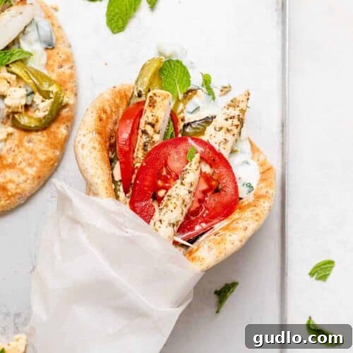 Delicious chicken gyros on a baking sheet, showcasing the cooked chicken, roasted vegetables, and creamy baked feta.