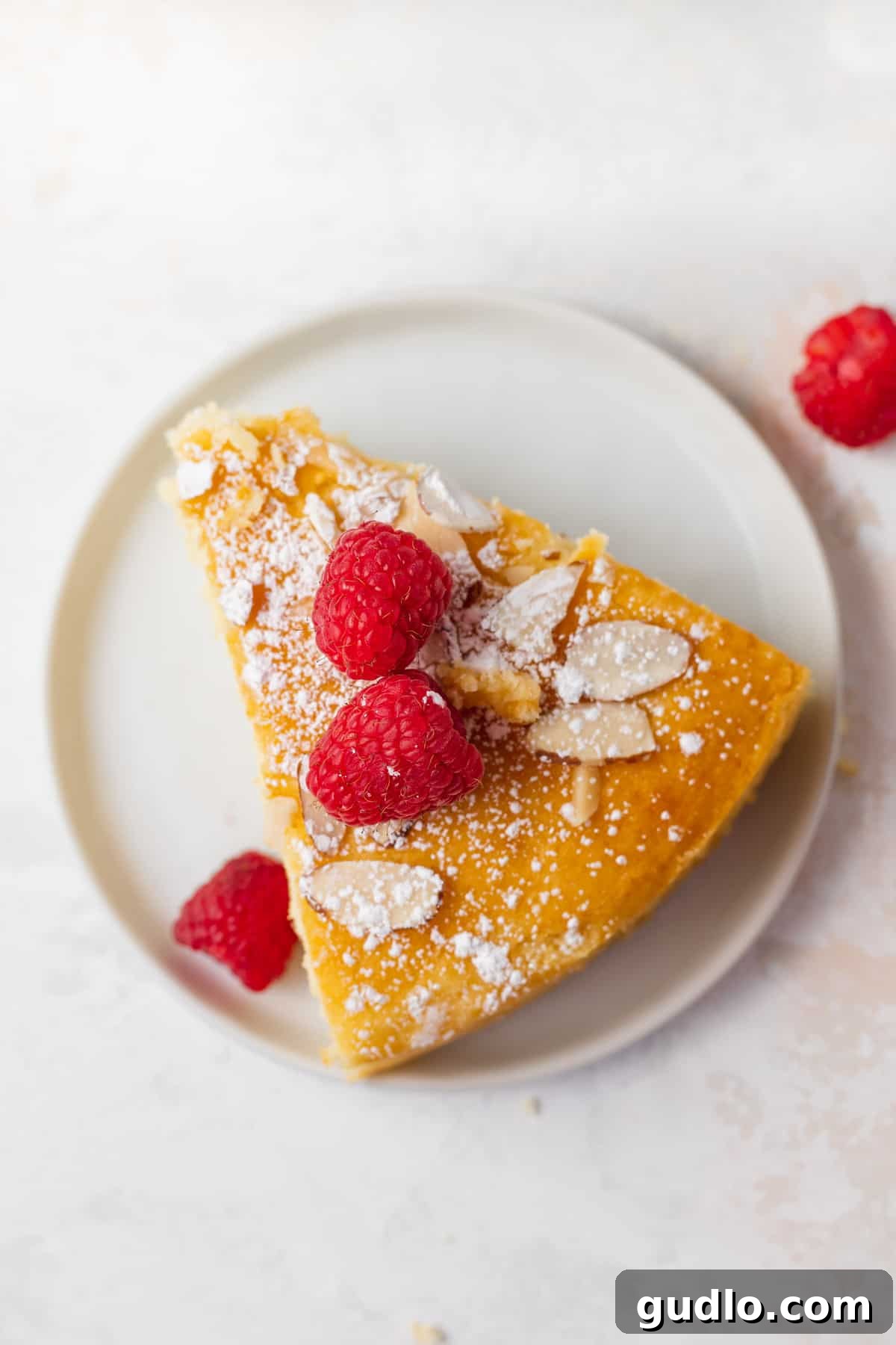Make any occasion special with this deliciously fluffy and moist lemon ricotta cake that's made from 9 simple ingredients. Enjoy! A delicious slice of lemon ricotta cake on a plate with fresh raspberries on top