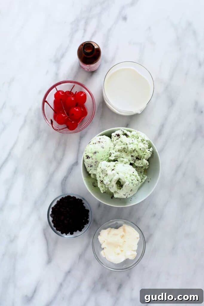 Creamy Mint Shamrock Shake 3 A collection of fresh ingredients for a Shamrock Shake, including mint chip ice cream, a carton of milk, a block of cream cheese, and a bottle of peppermint extract, all neatly arranged in bowls and containers.