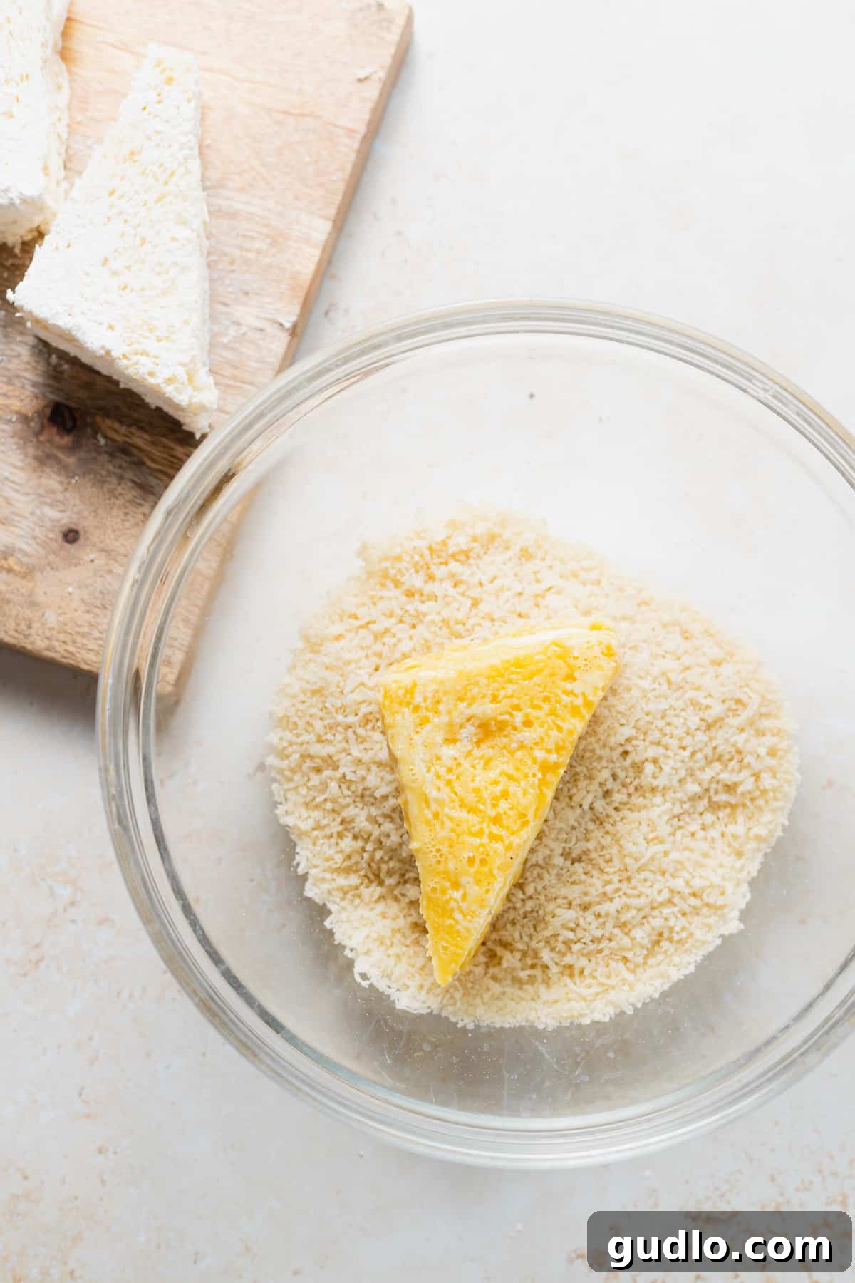 Coating the sandwich in breadcrumbs for frying Mozzarella in Carrozza sandwich being dredged through a bowl of breadcrumbs and Parmesan cheese