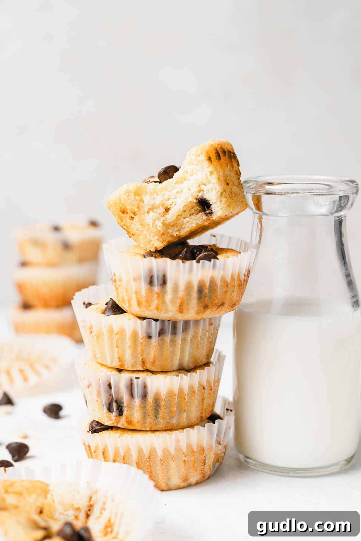 Fluffy Chocolate Chip Ricotta Muffins with Milk Delicious chocolate chip ricotta muffins in muffin liners next to a glass of refreshing milk, inviting you to take a bite.