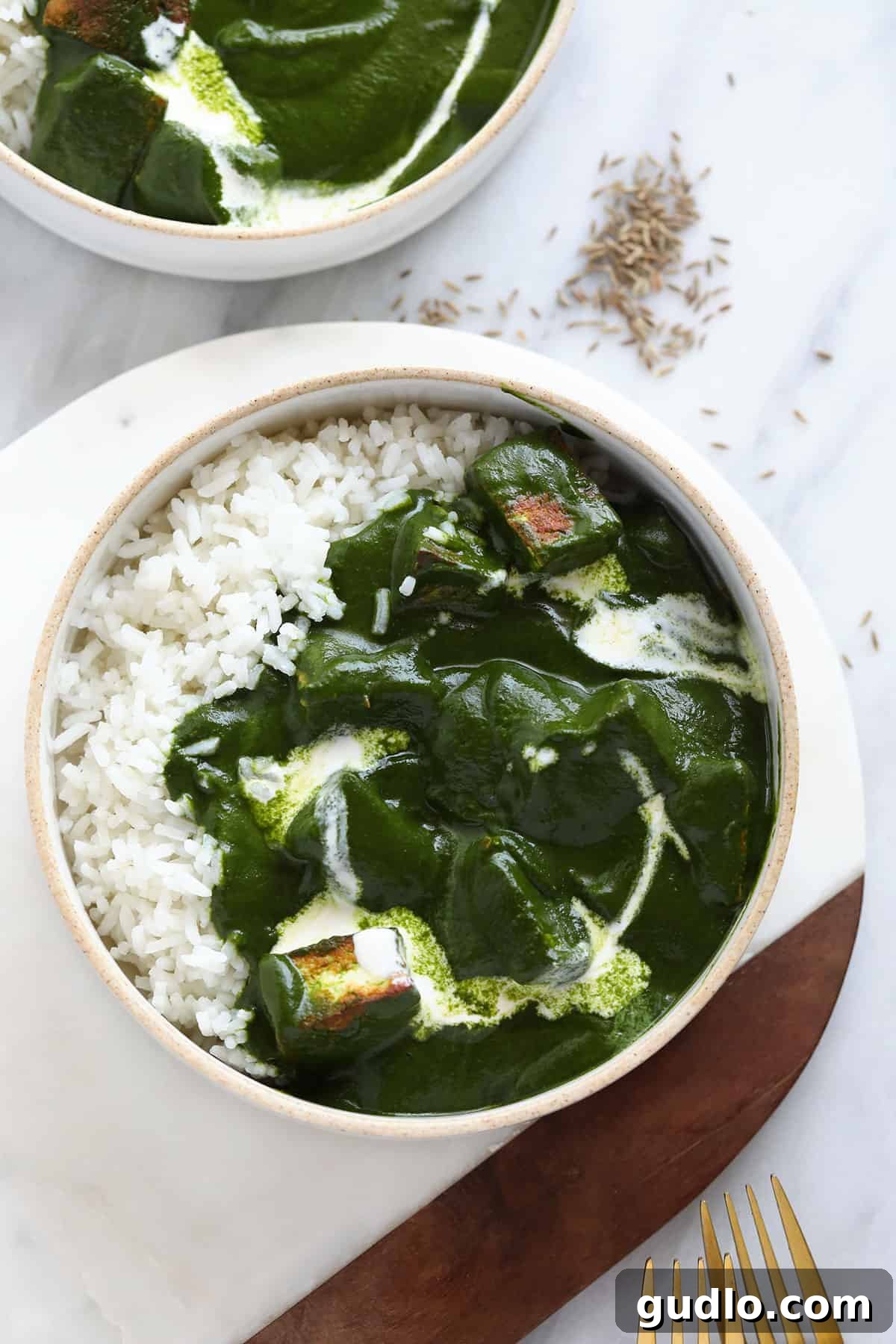 Emerald Spinach and Cottage Cheese Delight 2 A vibrant bowl of Palak Paneer served alongside fluffy rice, garnished with a swirl of cream. This dish is veggie-packed, creamy, and a delicious dinner option.