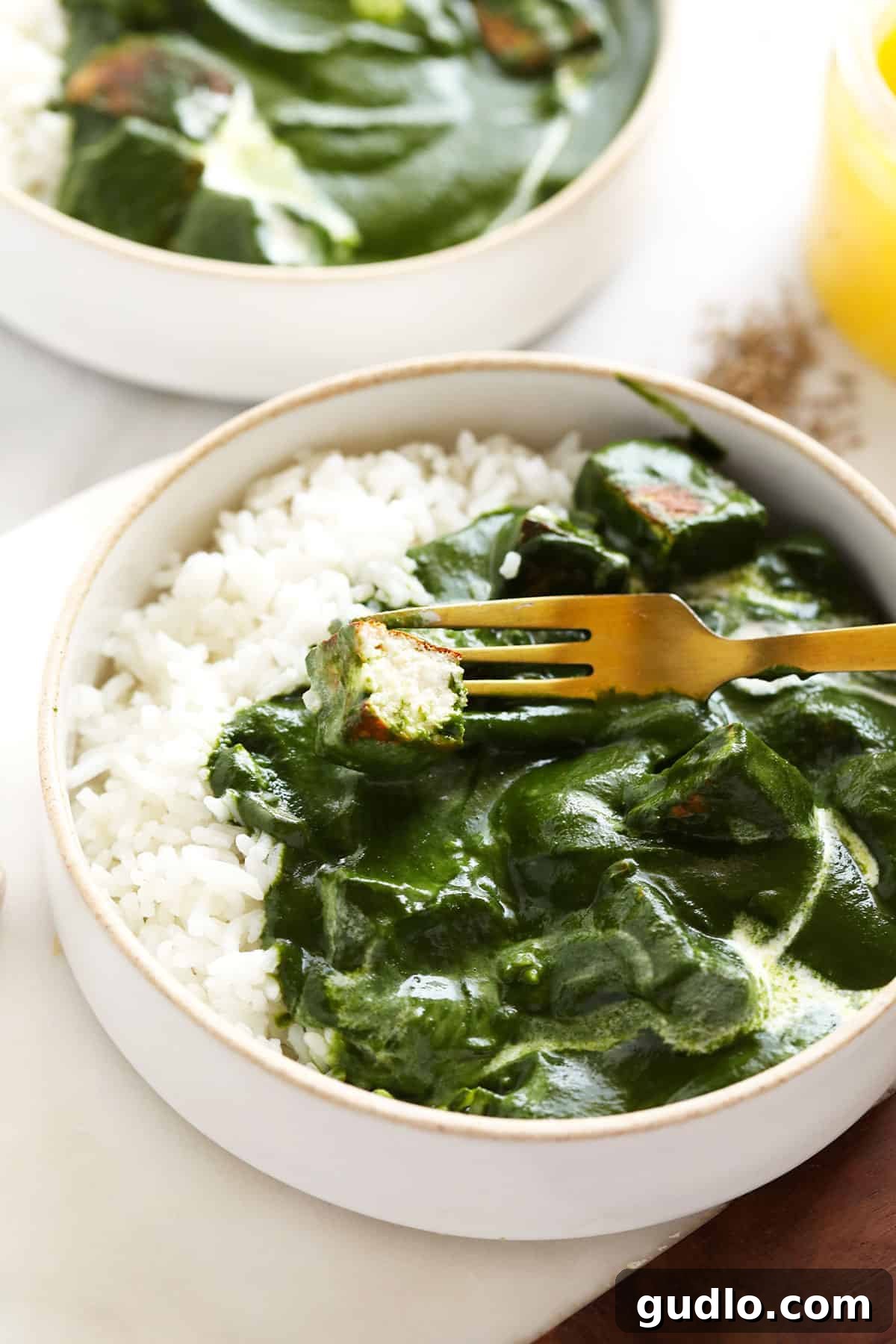 Emerald Spinach and Cottage Cheese Delight 11 A fork piercing a cube of paneer, glistening with the creamy spinach curry, ready to be enjoyed with rice, naan, and chutney.