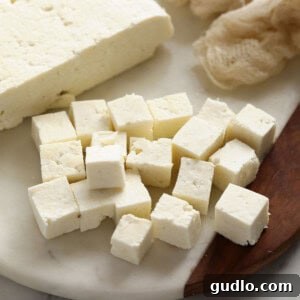 Emerald Spinach and Cottage Cheese Delight 4 Cubes of freshly made paneer cheese neatly arranged on a wooden cutting board, ready to be cooked.