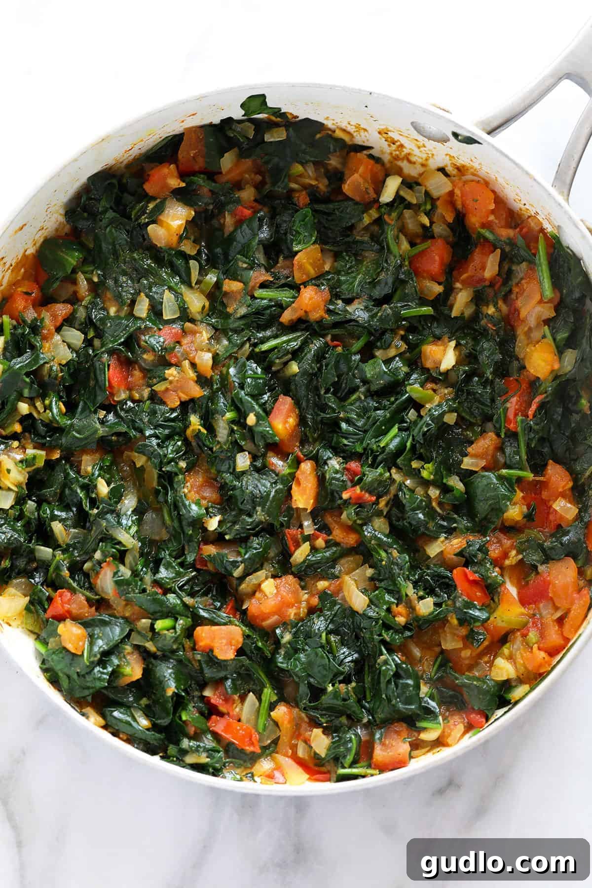 Emerald Spinach and Cottage Cheese Delight 7 Fresh spinach wilting down with other aromatic ingredients in a pan, steaming under a lid.