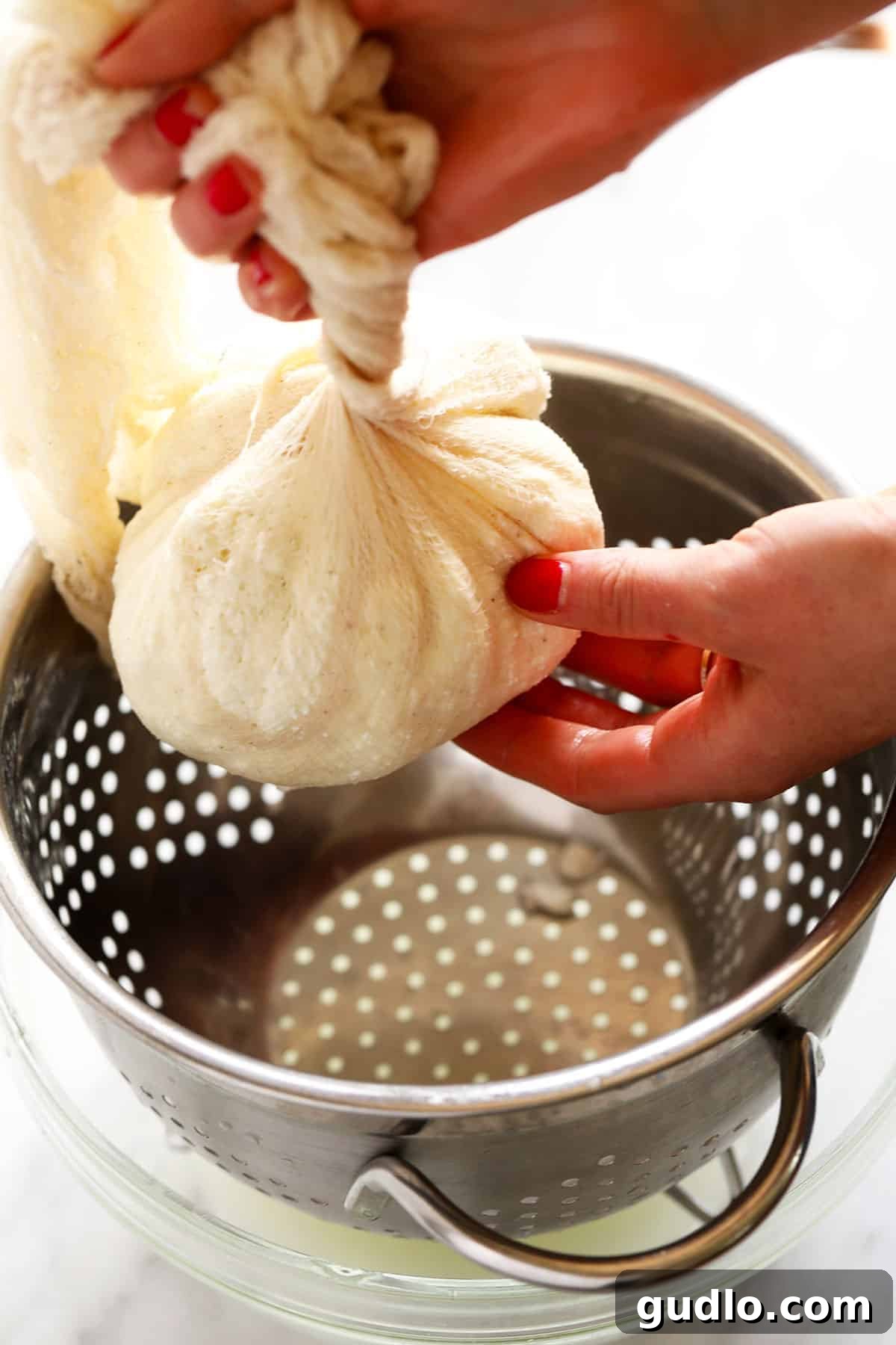 Crafting Fresh Paneer at Home 6 Hands gently twisting a cheesecloth full of paneer curds to squeeze out excess whey, forming a round ball.