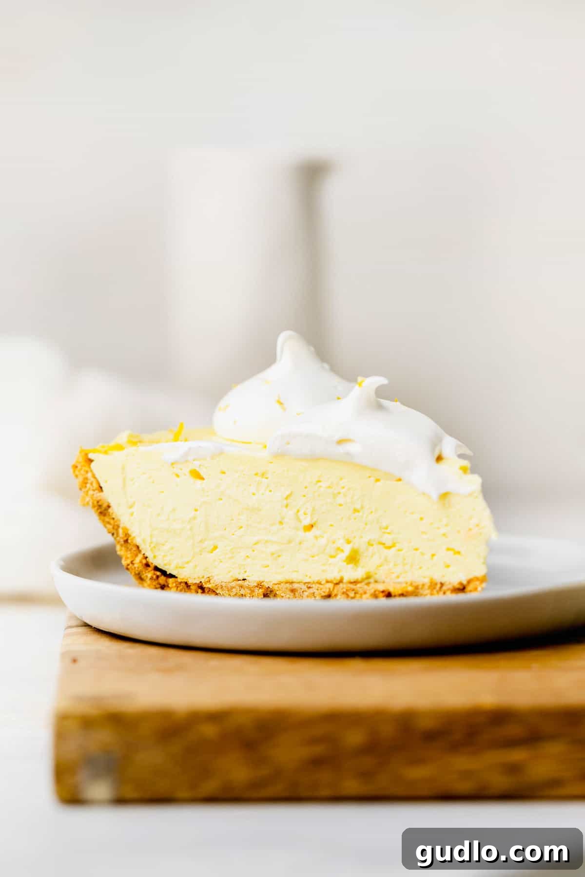 A perfect slice of creamy, zesty cream cheese lemonade pie on a white plate, highlighting its smooth texture and golden crust.