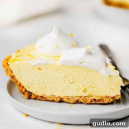 A tempting slice of creamy lemon pie on a simple white plate, ready for serving.