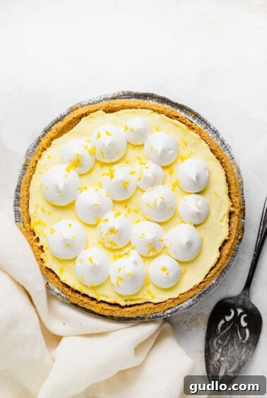 A finished cream cheese lemonade pie generously topped with whipped cream and vibrant lemon zest, ready to be served.