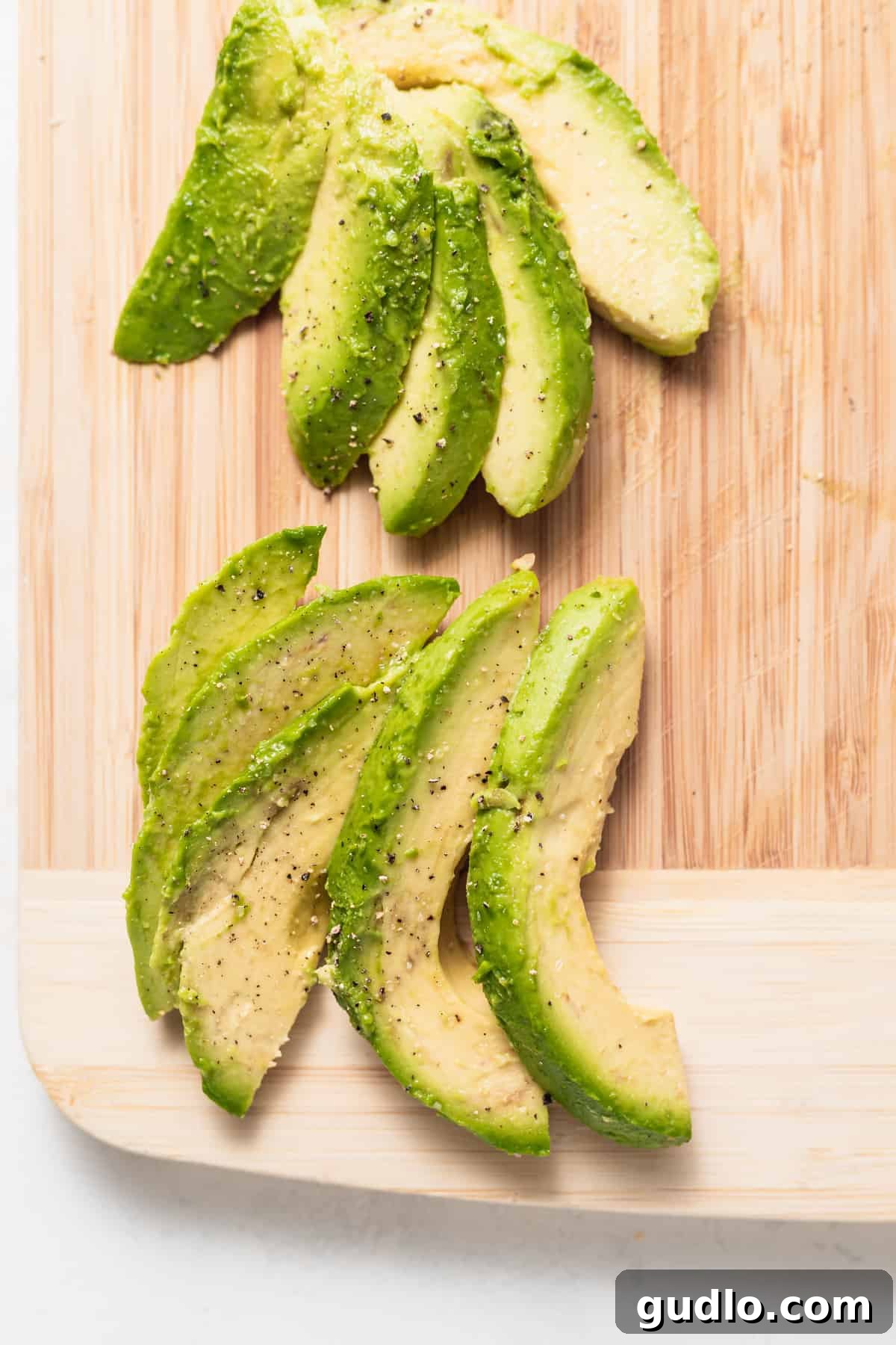How to Select and Slice Perfect Avocados Freshly sliced avocado fanned out on a wooden cutting board, ready for use.