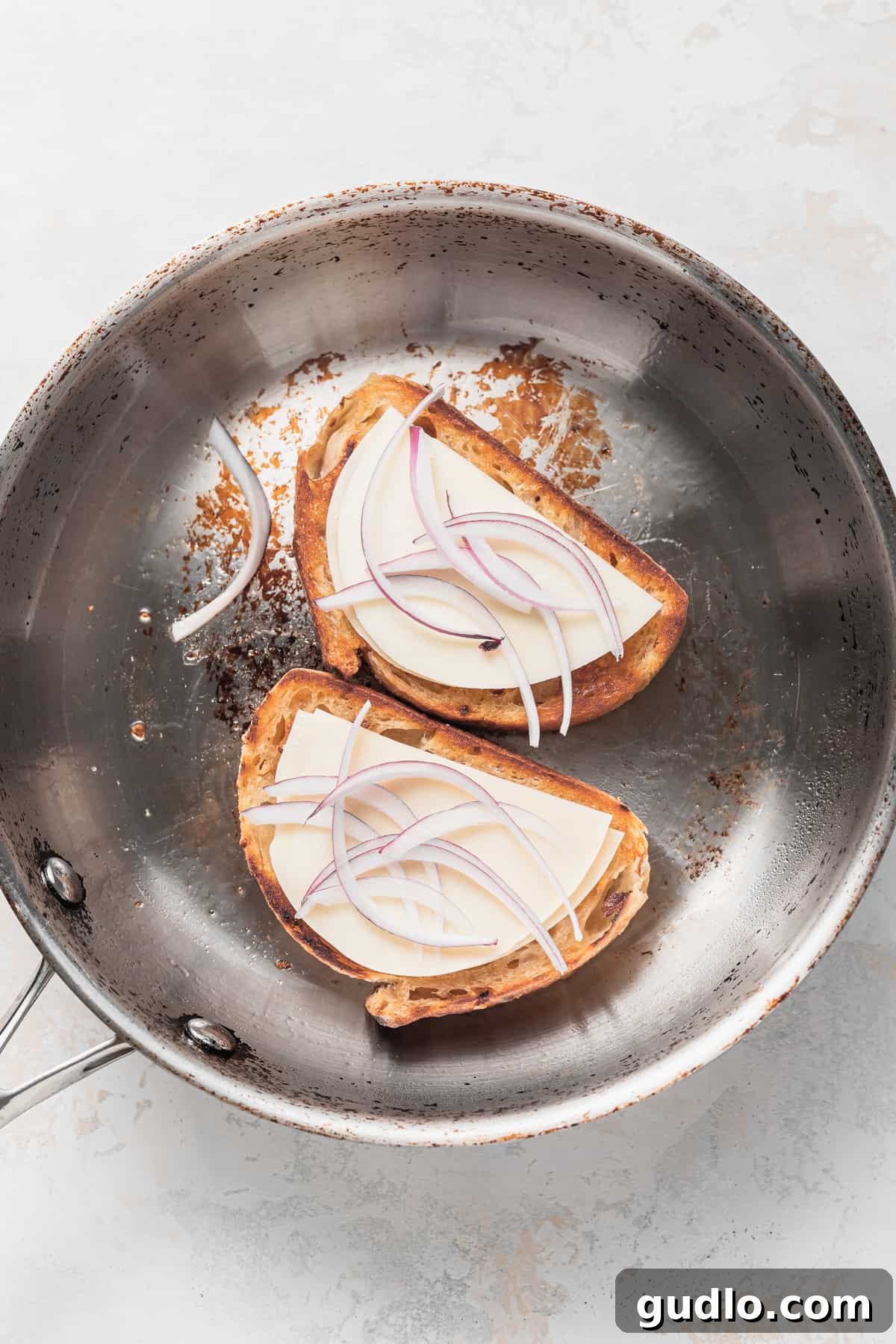 Assembling the Perfect Avocado Grilled Cheese Sourdough bread, provolone cheese, and thinly sliced red onion arranged in a pan, ready for grilling.