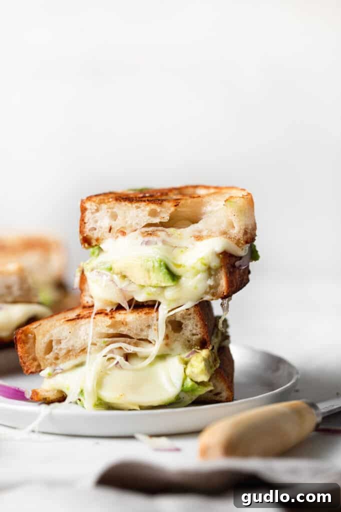 Irresistibly Cheesy Avocado Grilled Cheese Beautifully melted cheesy avocado grilled cheese, sliced in half and ready to serve.