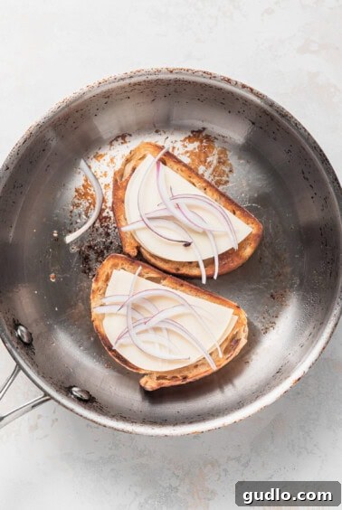 Assembled grilled cheese with cheese in a pan, awaiting more fillings.