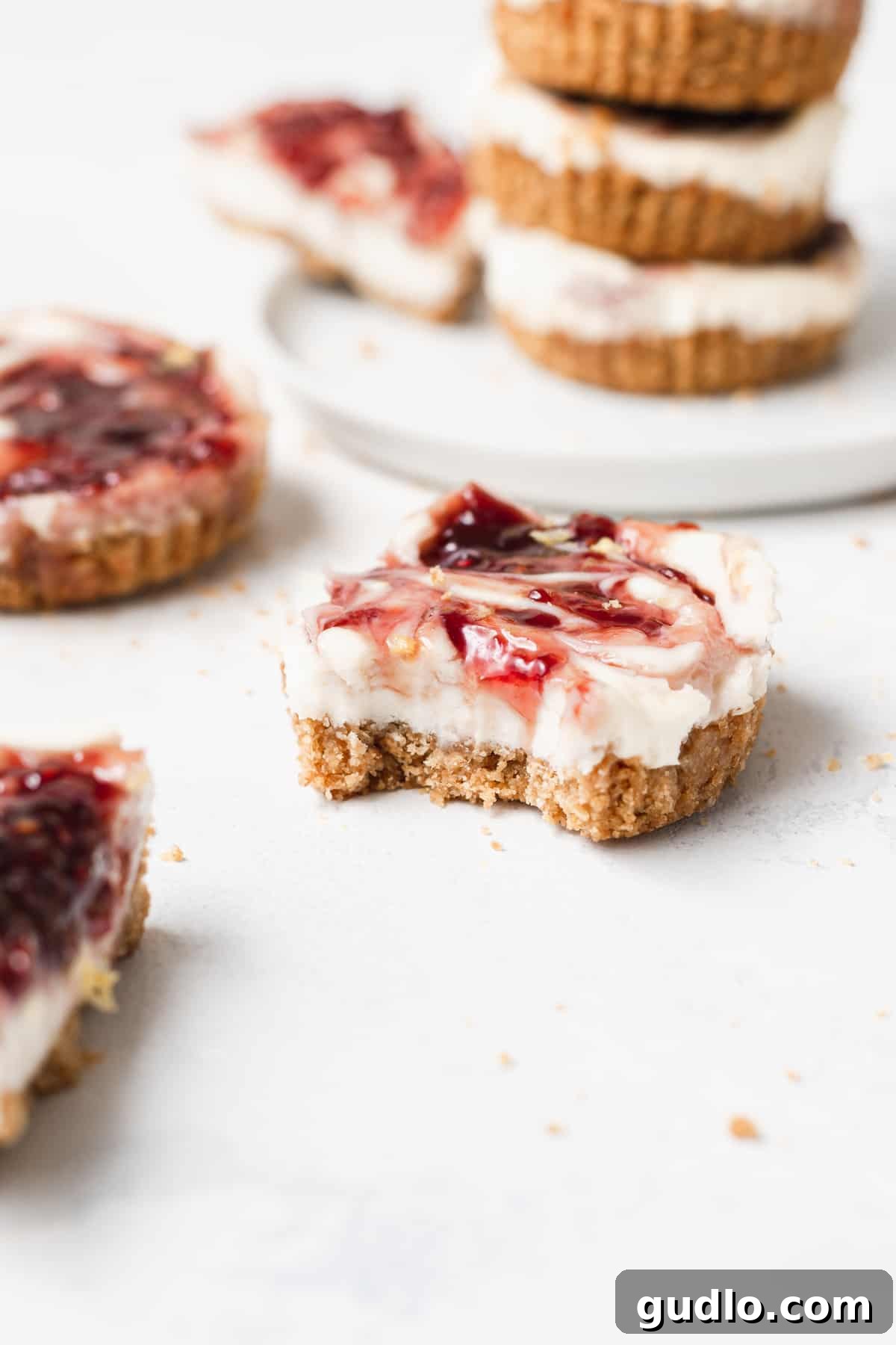 Bite-Sized Cheesecake Delights 2 A lemon raspberry cheesecake bite with a small portion taken out, showing the creamy filling and a hint of raspberry swirl.