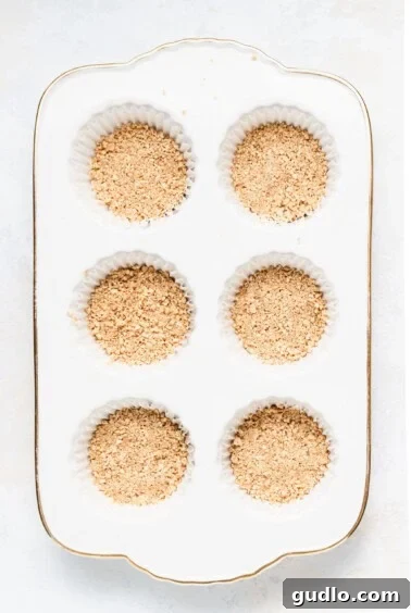 Perfectly pressed graham cracker crusts in a muffin tin, ready for the filling.