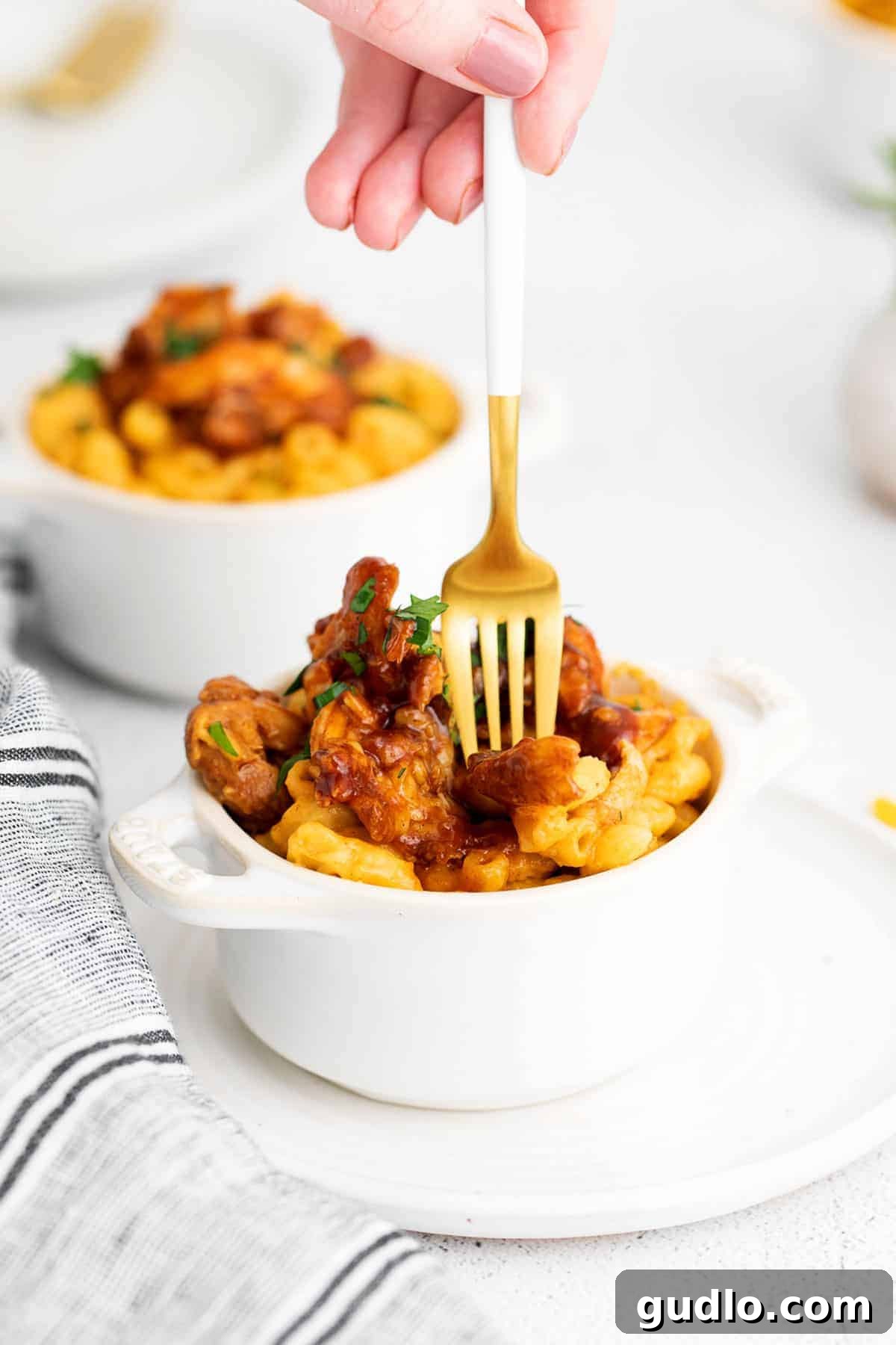 A fork taking a bite of BBQ chicken mac and cheese, showcasing creamy pasta and tender chicken pieces.