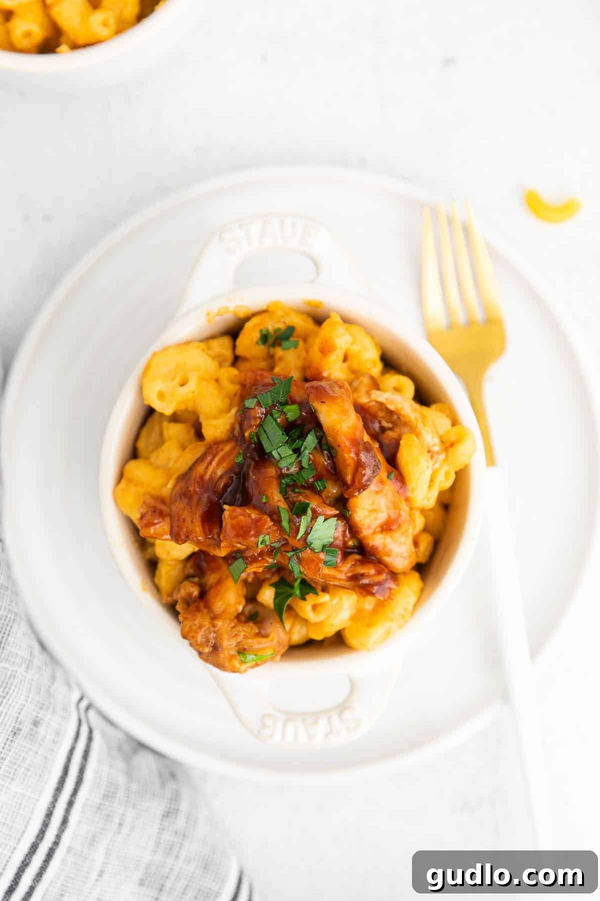 A small bowl of BBQ Chicken Mac and Cheese, perfectly portioned and ready to enjoy, topped with fresh herbs.