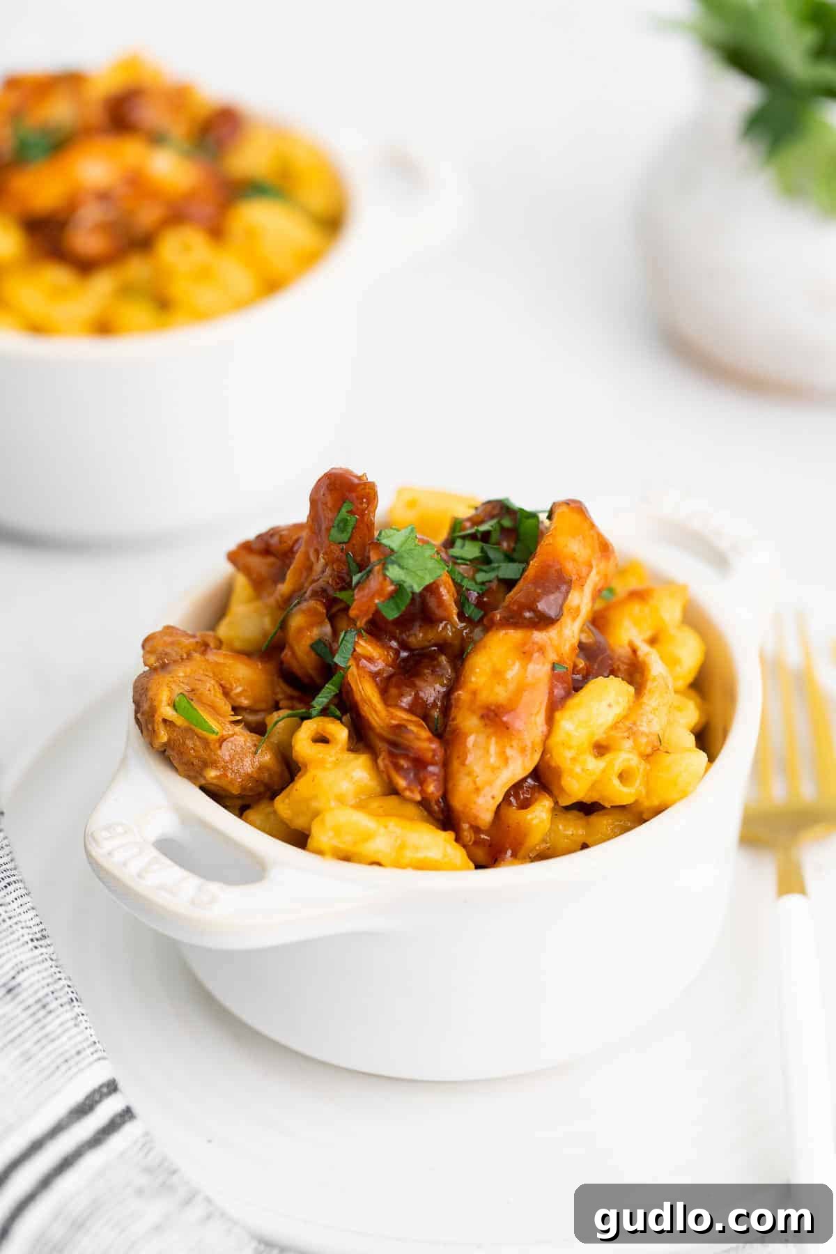 A bowl of creamy BBQ Chicken Mac and Cheese, garnished and ready to serve.