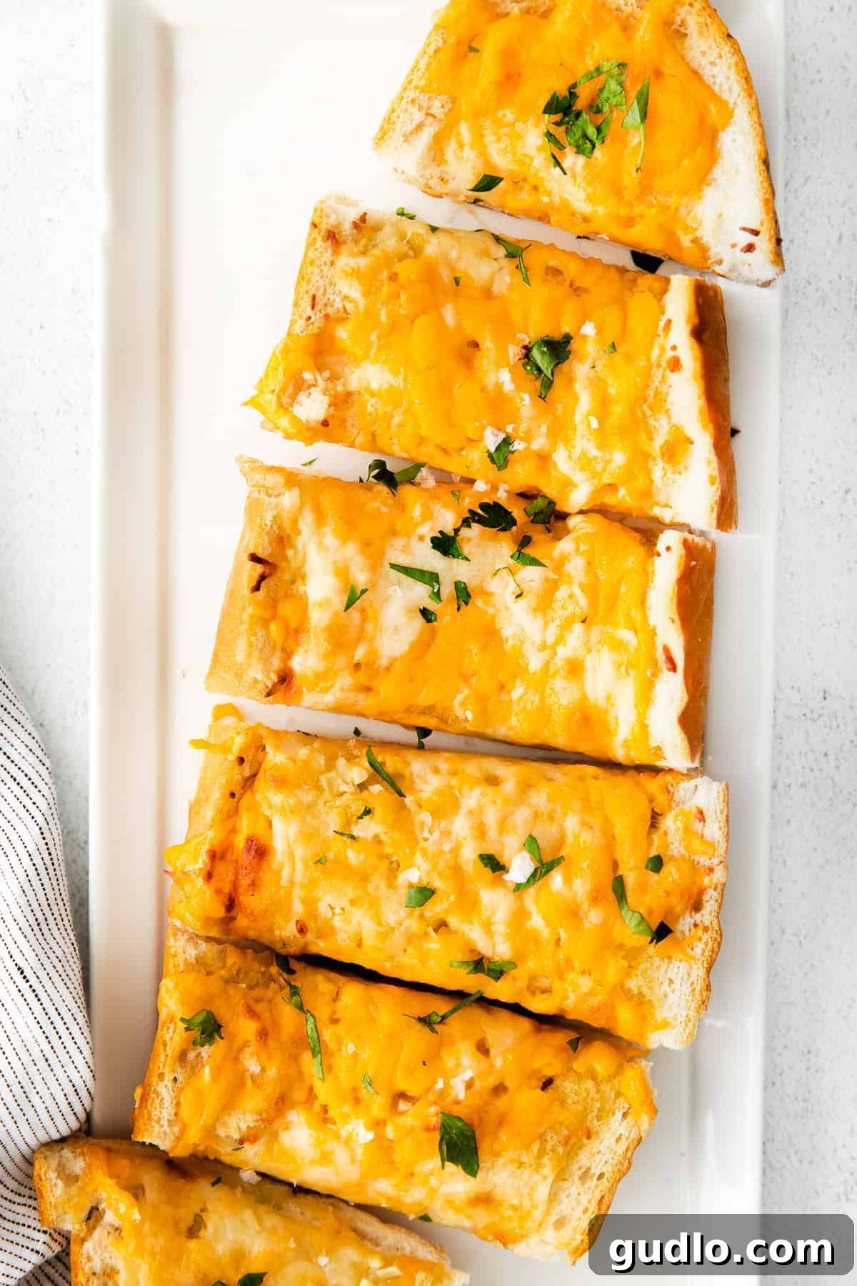 Golden Cheesy Garlic Bliss 2 Golden brown cheesy garlic bread on a white platter, ready to be served.