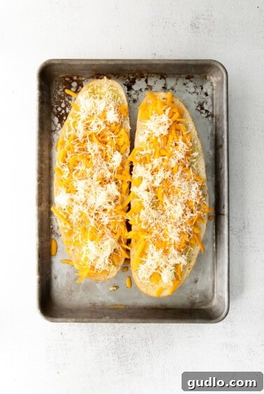 Golden Cheesy Garlic Bliss 13 Garlic bread with cheese sprinkled over the top on a baking sheet.
