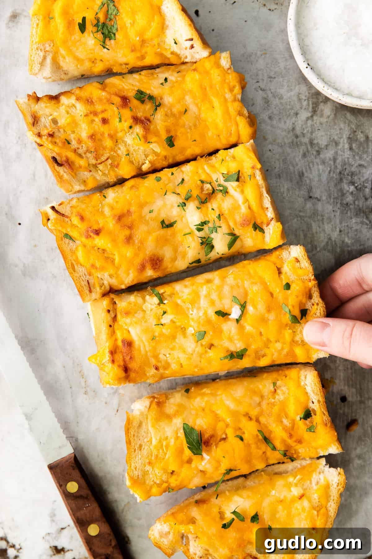 Golden Cheesy Garlic Bliss 9 Cheesy garlic bread garnished with fresh chopped parsley on a wooden board.