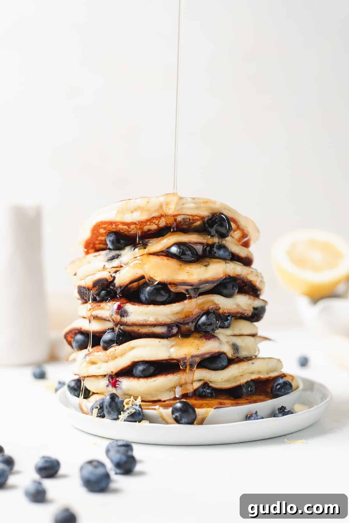 Stack of fluffy blueberry ricotta pancakes drizzled with maple syrup
