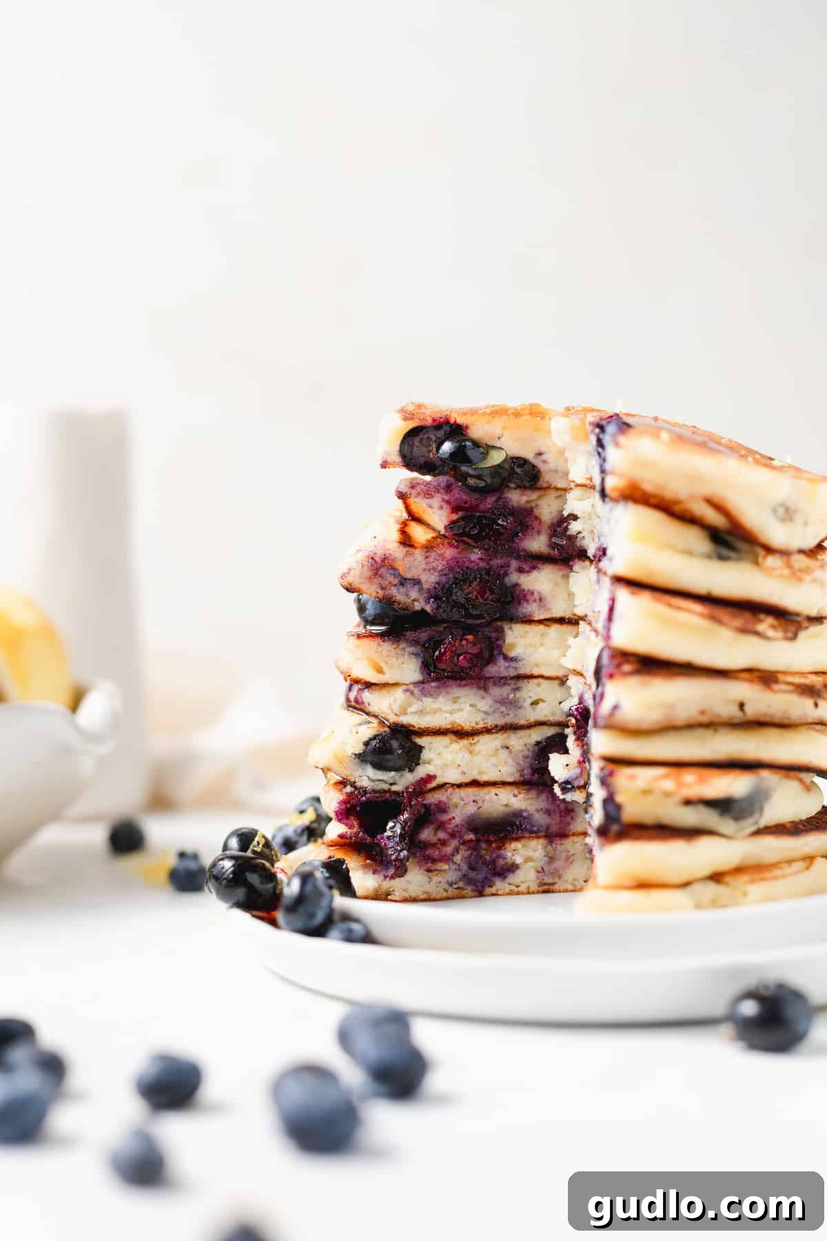 Stack of blueberry ricotta pancakes with a slice removed, revealing fluffy interior