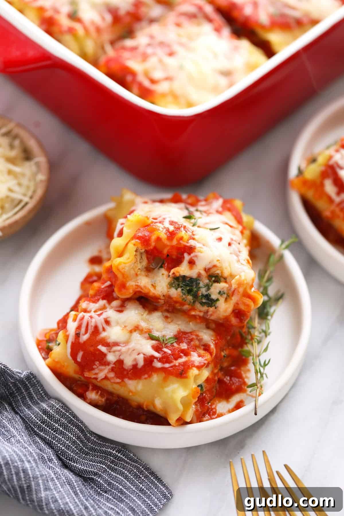 Wholesome Kale Lasagna Roll Ups 7 Two individual Kale Lasagna Roll Ups served on a plate, garnished with fresh herbs.