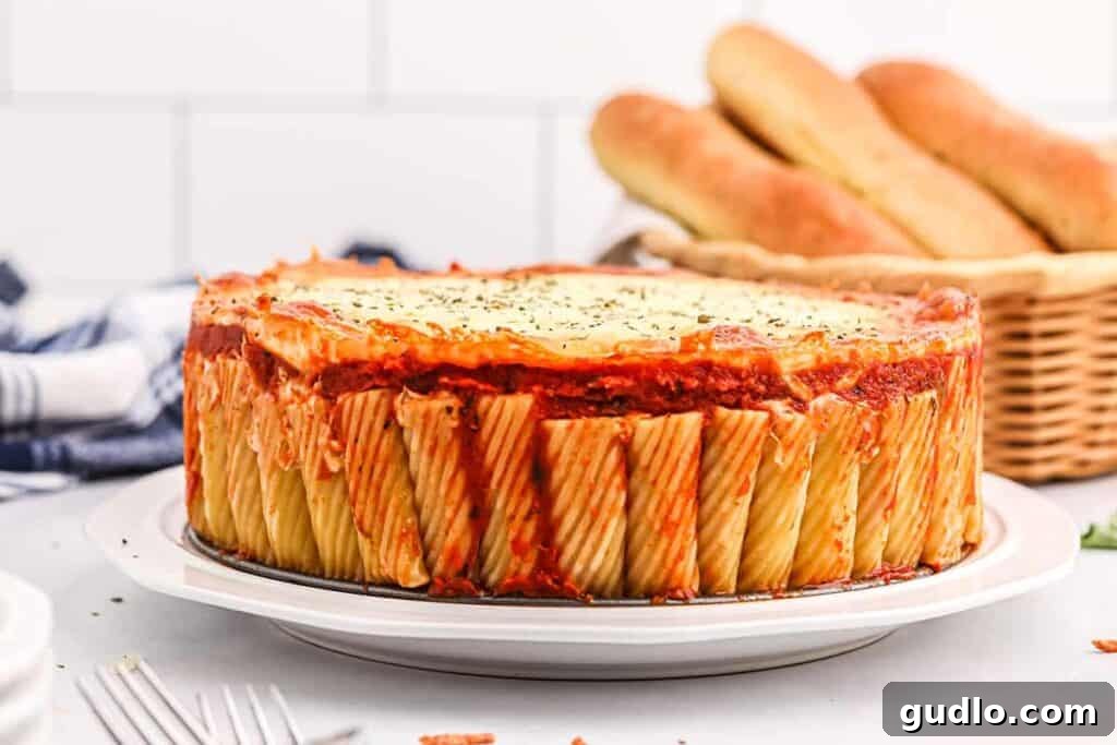 Rigatoni pie on plate, ready to be enjoyed. A single slice of baked Rigatoni Pie, garnished with fresh basil, served on a white plate.