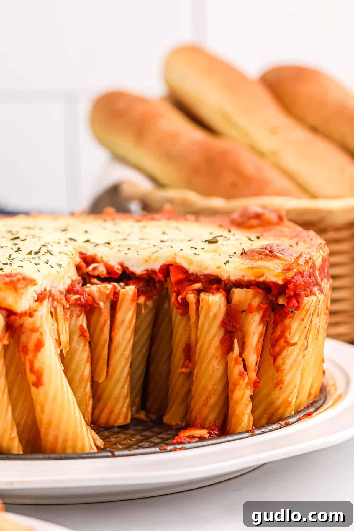 Rigatoni pie with cheese, a delicious baked pasta dish. A large, golden Rigatoni Pie, topped with melted mozzarella cheese and fresh basil, presented on a rustic wooden board.