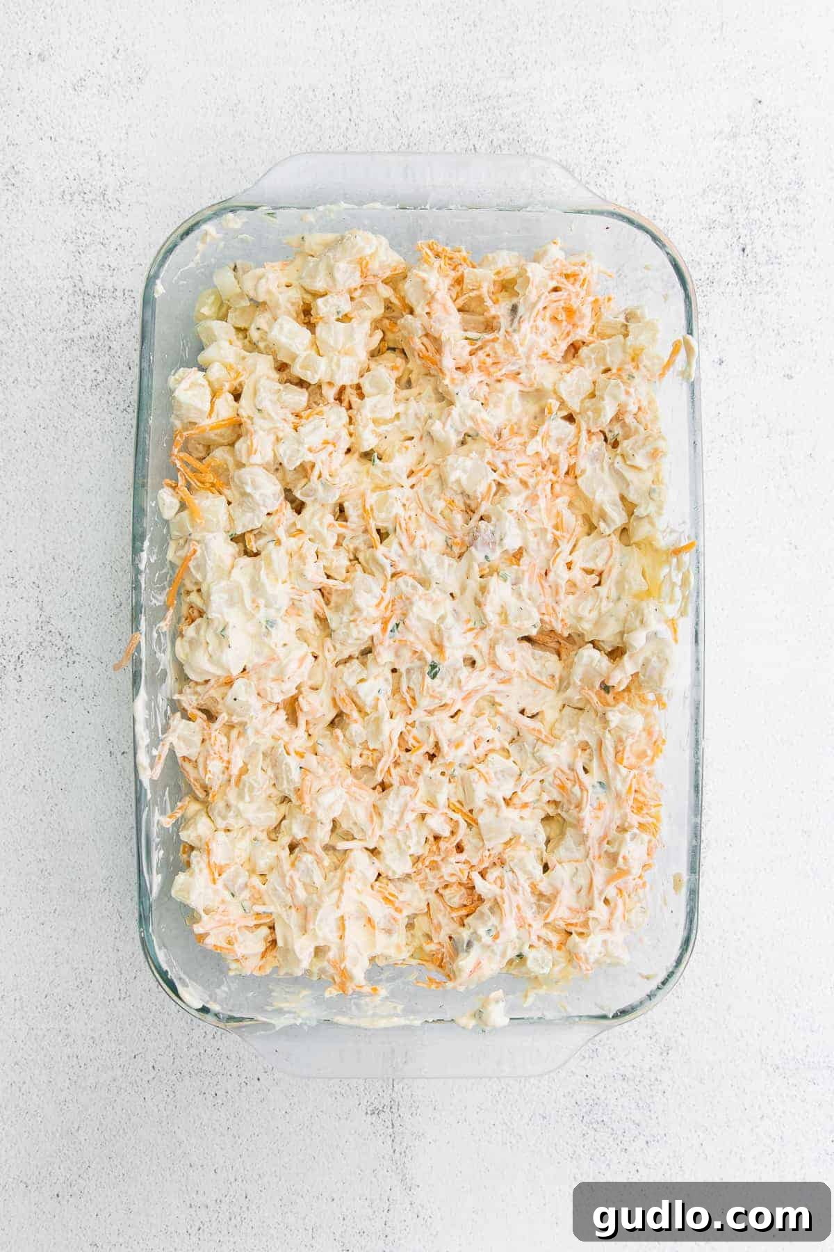 Pre-baked Cheesy Hashbrown Casserole Uncooked cheesy hashbrown casserole mixture in a baking dish, ready for the oven.