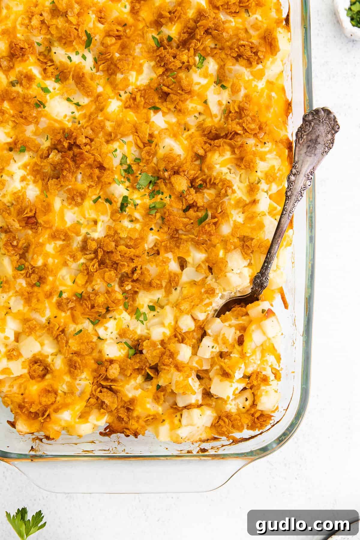 Delicious Cheesy Hashbrown Casserole Cheesy hashbrown potatoes in a casserole dish, garnished with fresh herbs, ready to be served.