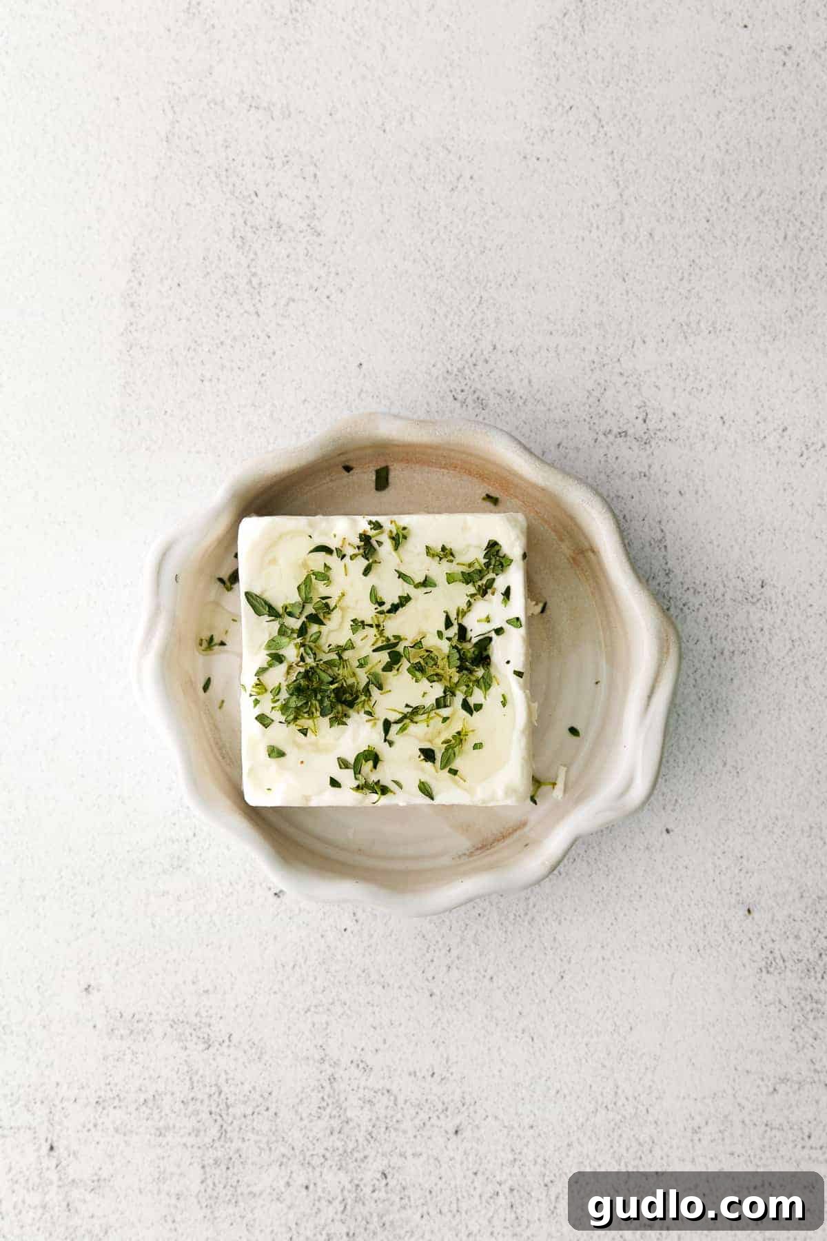 Flame-Kissed Feta 4 A close-up shot of a block of feta cheese expertly prepared with fresh thyme, olive oil, a sprinkle of salt, and a drizzle of honey, ready for grilling or serving.