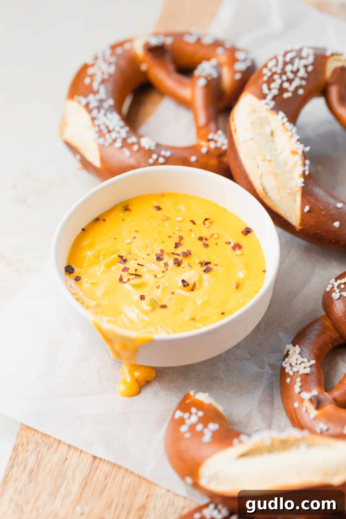 Get dipping, cheese lovers! This pretzel cheese dip is super creamy and easily made on the stove-top. Pair with soft pretzels, and enjoy this ultimate appetizer! Creamy pretzel cheese dip in a rustic bowl, surrounded by golden soft pretzels ready for dipping.