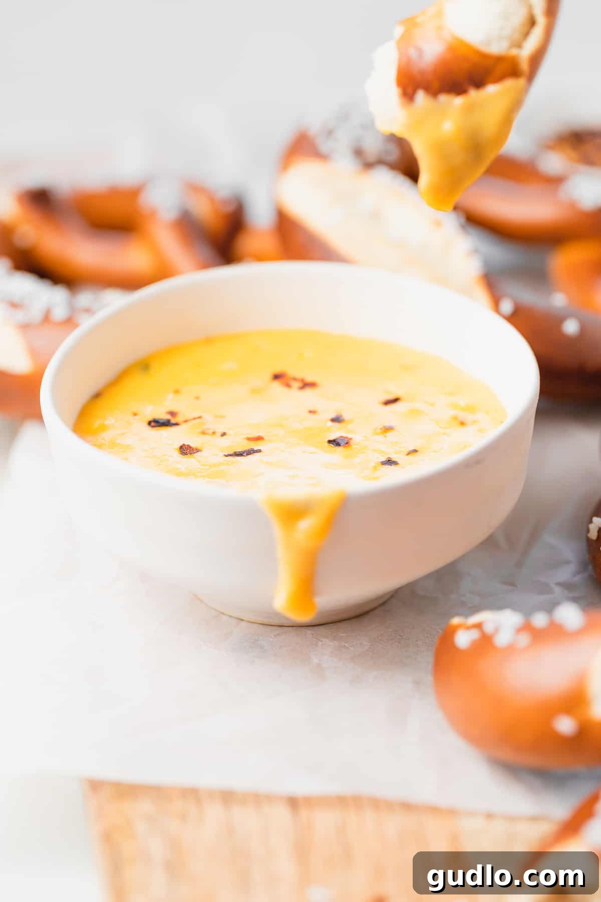 pretzel cheese dip looking melty and delicious in a bowl A close-up shot of the pretzel cheese dip in a bowl, showcasing its rich, golden color and smooth, melty consistency.