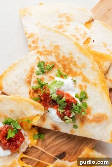 A freshly cooked and sliced cheese quesadilla resting on a wooden cutting board, ready to be enjoyed.