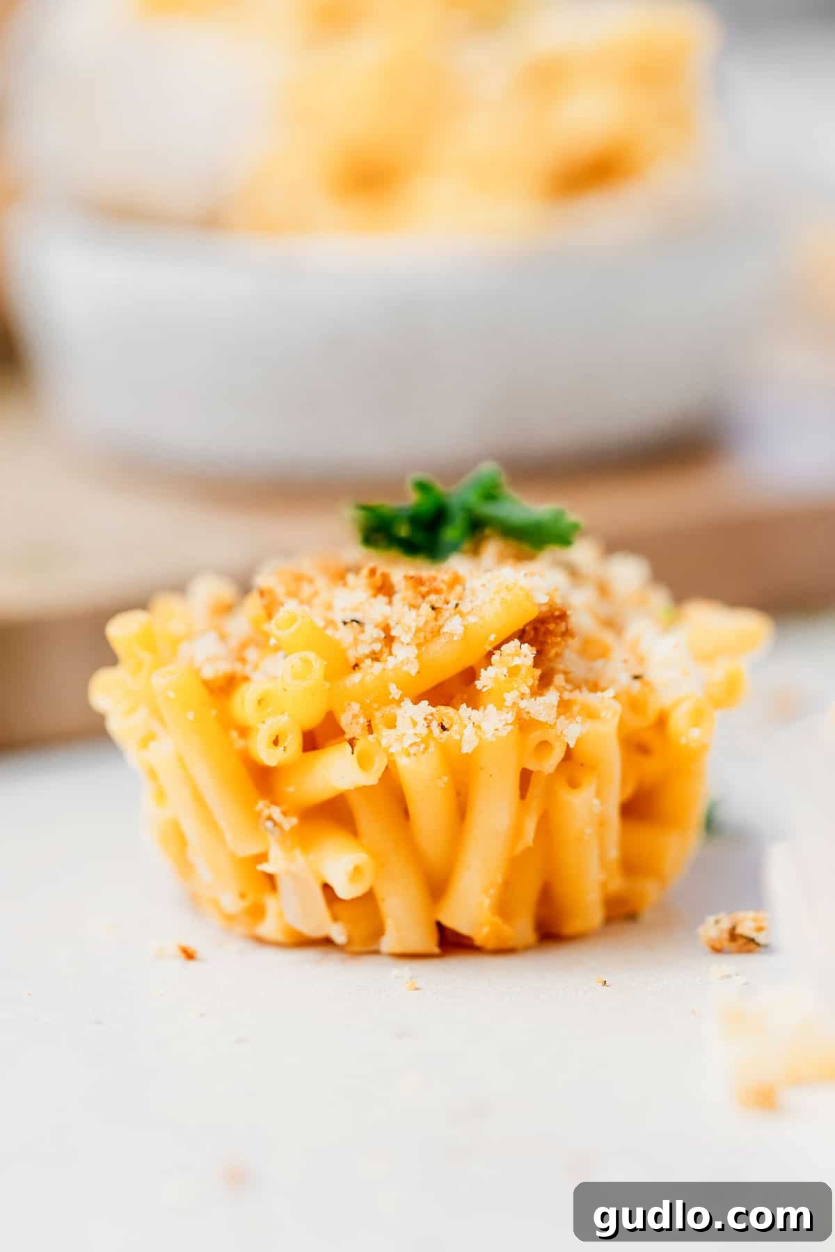 Elevate your boxed mac and cheese into fun, kid-friendly mac and cheese cups – a perfect snack or side! Golden brown mac and cheese cup on a kitchen counter, ready to be enjoyed.