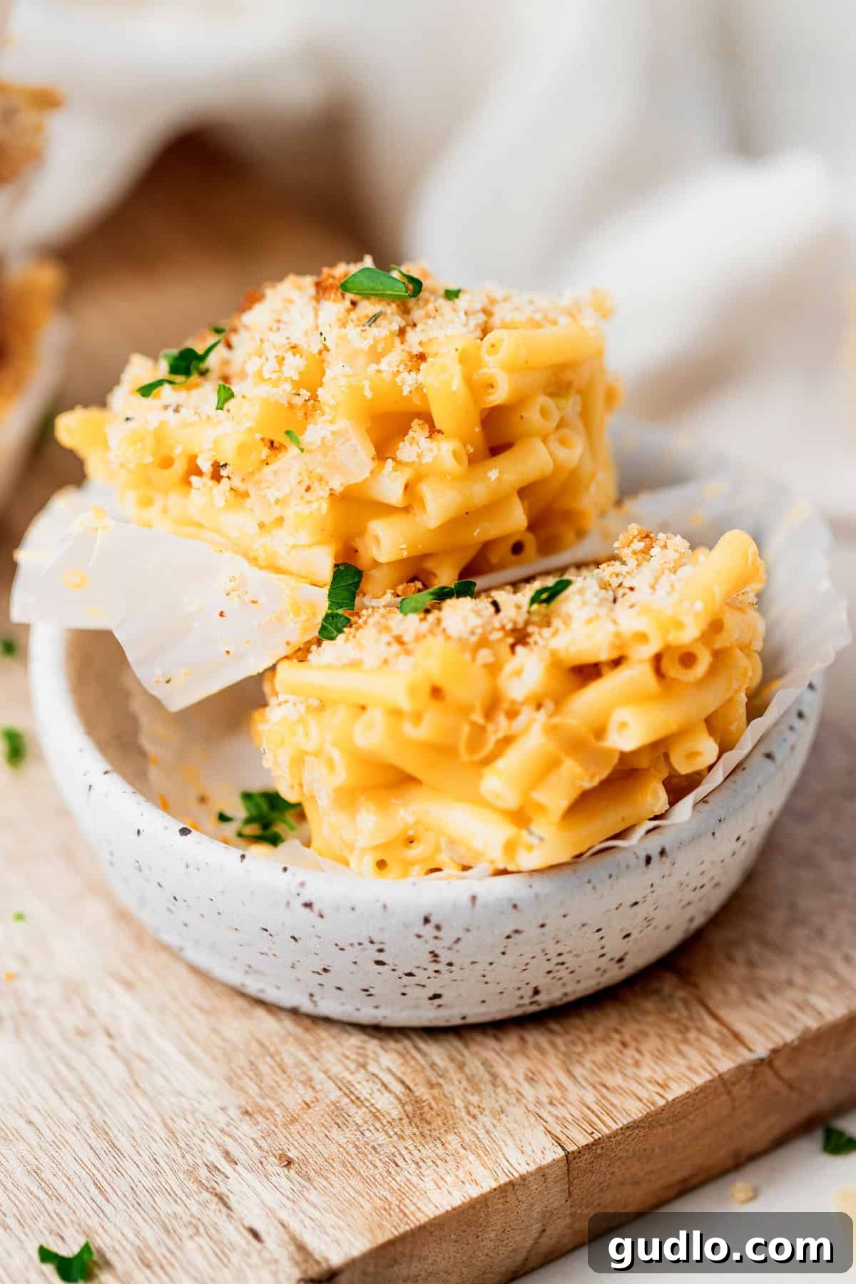 Baked Mac and Cheese Cups are a fun and easy way to enjoy mac and cheese, made with boxed mix and simple ingredients! Stack of perfectly baked mac and cheese cups, showcasing their individual golden brown tops.