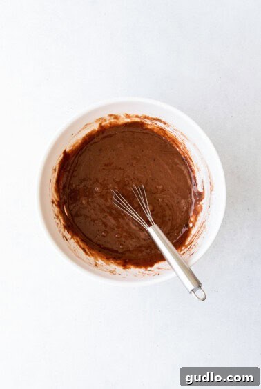 Chocolate cupcake batter in a white mixing bowl with a whisk.