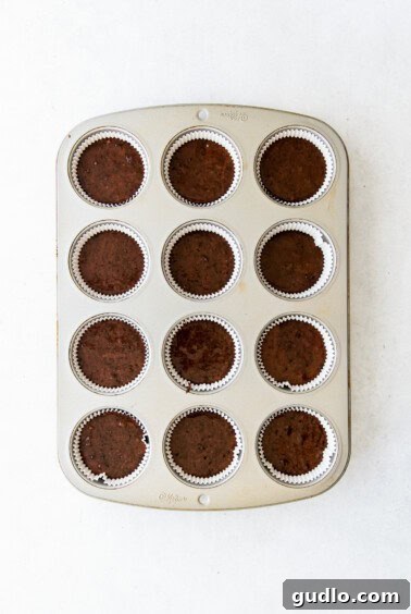 Chocolate cupcakes baking in a muffin tin.