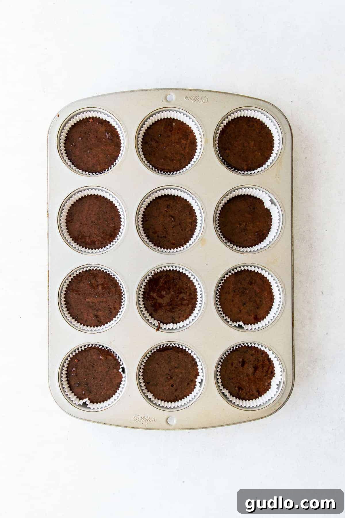 Freshly baked chocolate cupcakes cooling in a muffin pan, filling the kitchen with a sweet aroma.