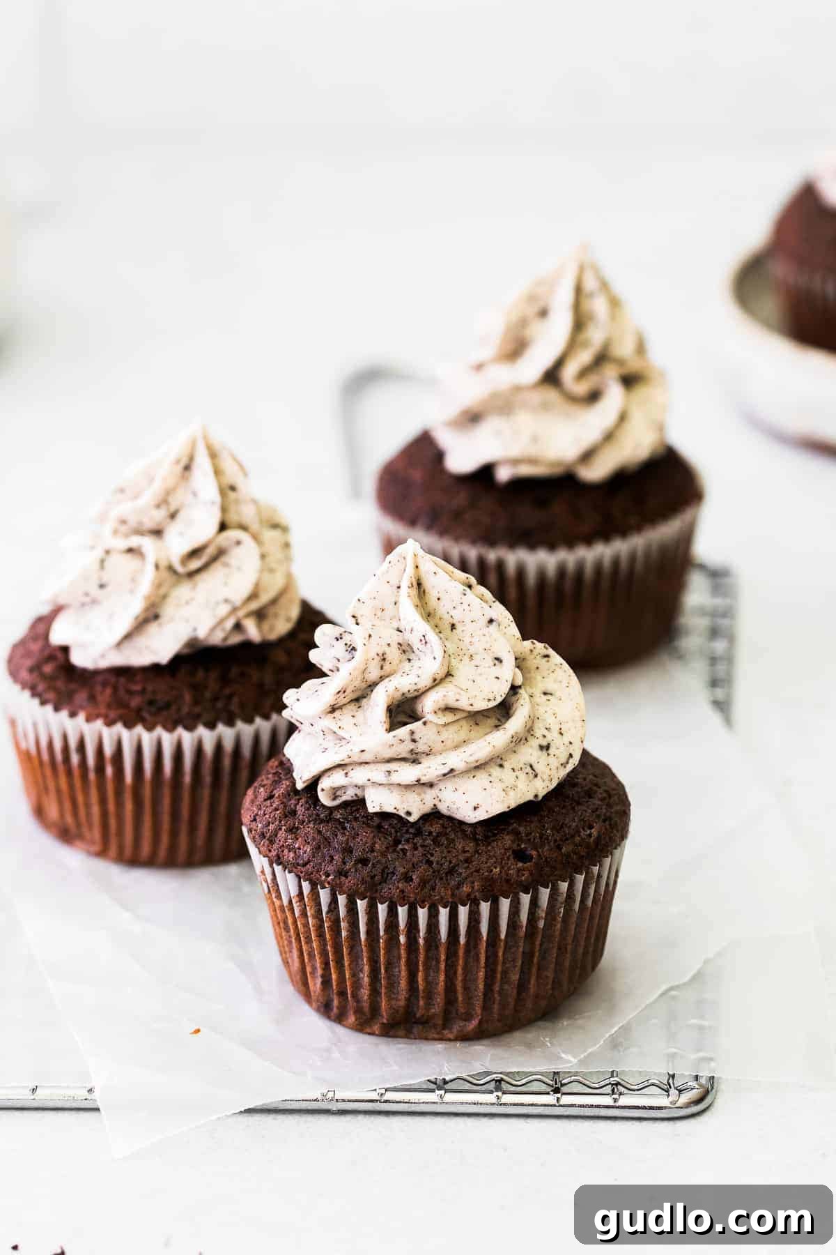 A single chocolate cupcake lavishly topped with rich cookies and cream frosting and an Oreo cookie piece.