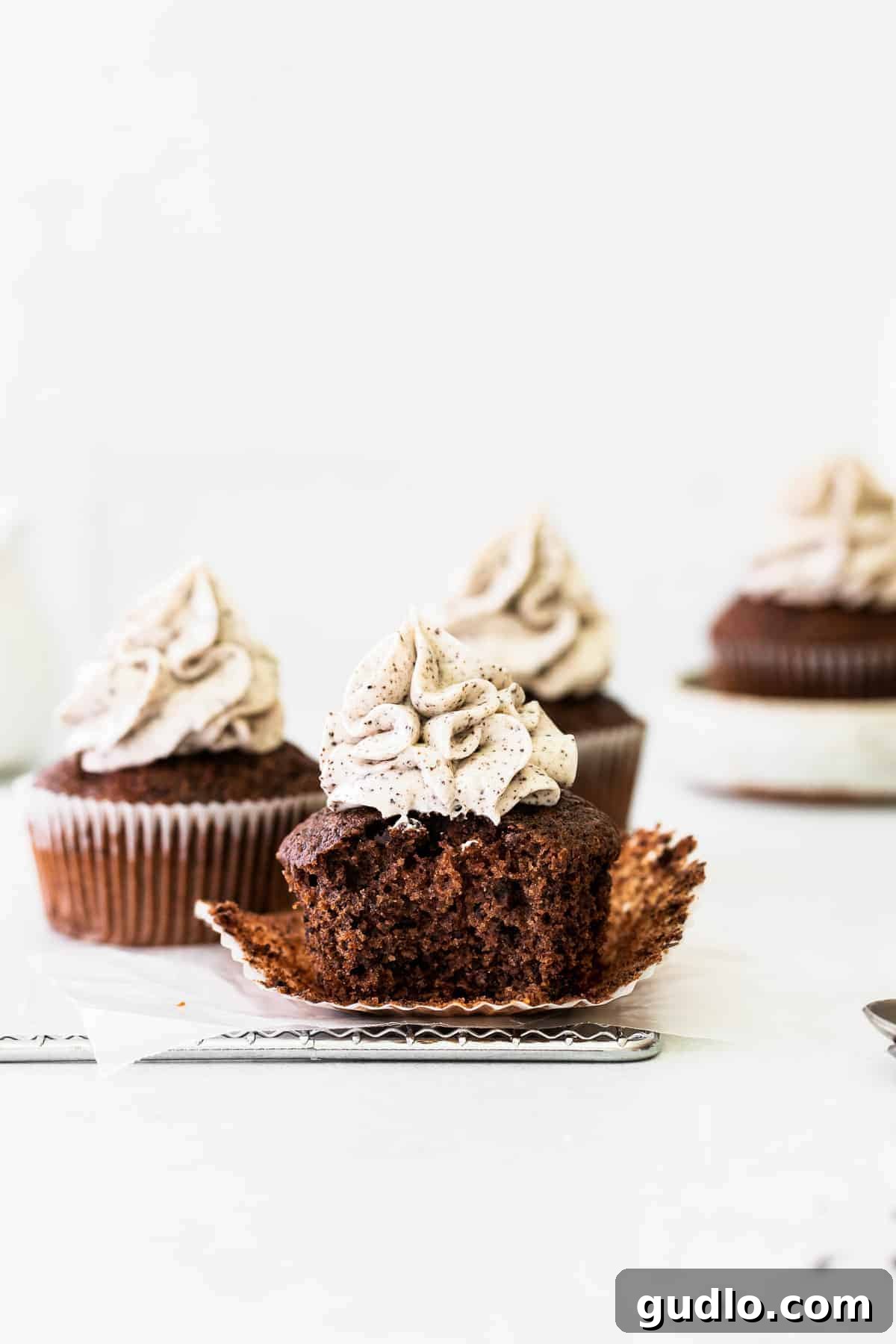 Freshly baked chocolate cupcakes arranged on a wire rack, awaiting their luscious frosting.
