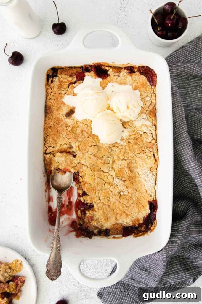 Cherry Cream Cheese Cloud Cake 2 A cherry cobbler with ice cream on top, served in a dish.