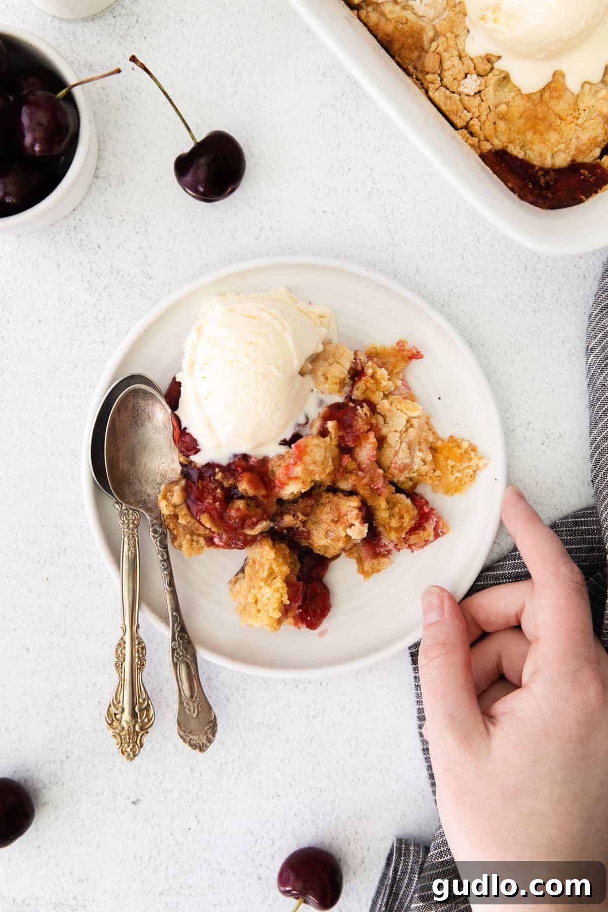 This Cream Cheese Cherry Dump Cake is calling your name! Dump all the ingredients into a cake pan, bake it, and enjoy topped with a scoop of vanilla ice cream. cherry dump cake on plate.