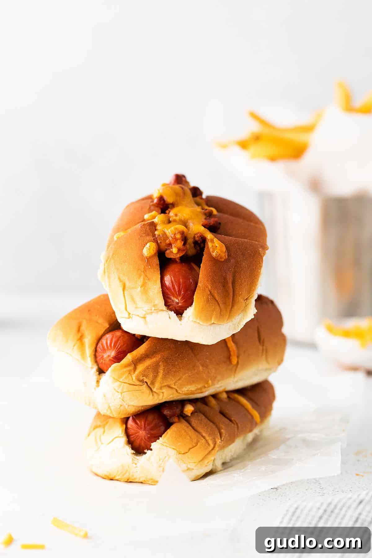 Stack of chili cheese dogs, topped with rich chili and melted cheese.
